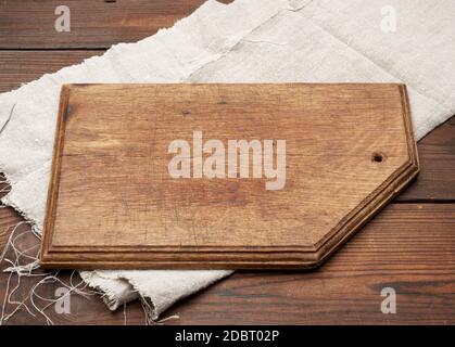 old brown rectangular wooden kitchen cutting board and gray linen napkin on the table, top view Stock Photo