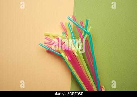 stack of plastic multi-colored cocktail tubes on a green background, close up Stock Photo
