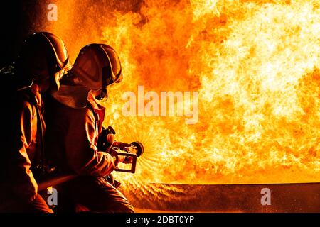 Firefighters using Twirl water fog type fire extinguisher to fighting with the fire flame from oil to control fire not to spreading out. Firefighter a Stock Photo