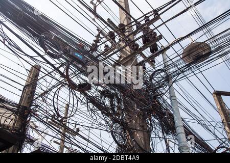 Messy entangled electricity, telecommunication wires, cables in under-developed city Stock Photo