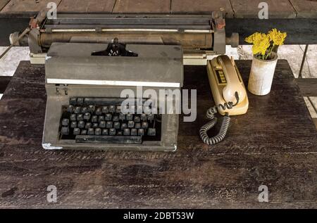 Vintage typewriter, old classic telephone and dry chrysanthemum flower on old wooden touch-up in still life concept Stock Photo