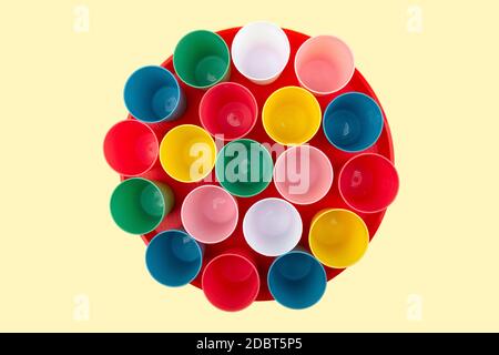 Empty Coloful plastic mugs on a red tray isolated on yellow background Stock Photo