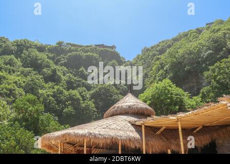 Wooden bungalow on white sand beach in tropical paradise. Wooden cottage with a reed roof on the island of Gili Meno in Indonesia. Simple bamboo fence Stock Photo