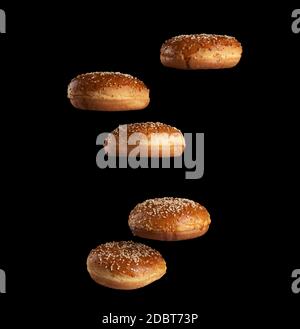 baked round sesame buns for sandwiches and hamburgers levitate on a black background crispy and appetizing pastries Stock Photo