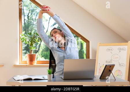 Beautiful women performing exercises and stretching in front of a laptop. Working at home, health concept. Stock Photo
