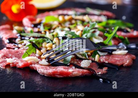 fresh carpaccio with rucola on slate Stock Photo