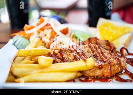 Closeup of grilled pork steak with salad on a plate, frenchfries and salad vegetables Stock Photo