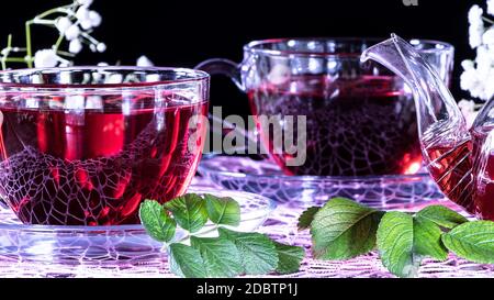 Hibiscus Red tea mug with carnation flowers close-up horizontal photo.English tea tradition.Medicinal therapy based on medicinal herbs and decoctions. Stock Photo