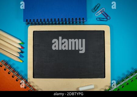 September still life with chalks and chalk board, spiral ring bound notebooks, pencils and scattered paper clips. Flat lay, view from above Stock Photo