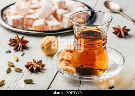 Tea in arab glass with turkish delight Rahat Lokum and different spices over wooden surface Stock Photo