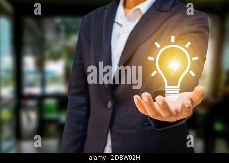 Business people hold energy-saving lamps and light bulbs for energy saving ideas and concepts and success. Stock Photo