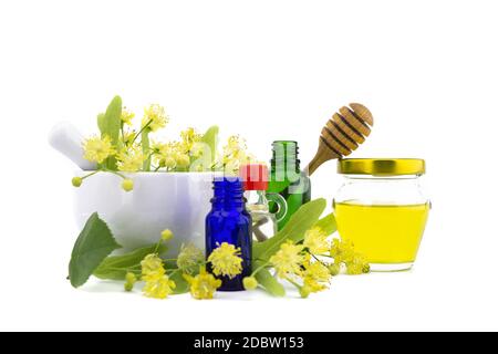 Fresh Linden or Tilia flowers and leaves with bottle of honey and essential oil bottles in a therapeutic still life for alternative healing Stock Photo