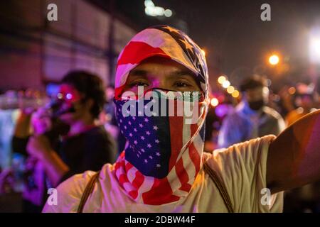 Bangkok, Bangkok, Thailand. 17th Nov, 2020. Demonstrator wearing a US flag scarf face covering, as hundreds of pro-democracy protesters gathered at Thailand's Parliament complex while the governing body was in session reviewing proposed amendment bills for the nation's constitution. When they began to move away concrete barricades set up to block their path the police used water cannon trucks and tear gas against the crowds. The confrontation went on for several hours until the police stood down, whereupon the protesters crossed the barricades and assembled outside of the parliament's gates Stock Photo