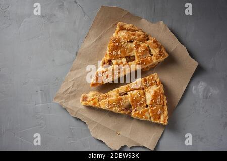 two baked pieces of apple pie on brown paper, top view, gray background Stock Photo