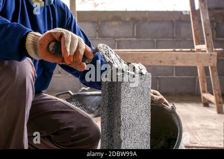 Close-up of construction workers using cement trowel on the brick to build walls in the construction industry. Stock Photo
