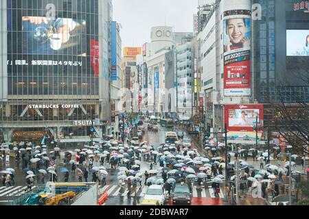 People Crossing A Crossroad On A Rainy Day In Tokyo, Japan Stock Photo