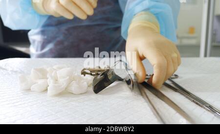 Close-up of the hands of a gynecologist in gloves. The doctor takes a speculum and other medical instruments to examine the woman. Unrecognizable phot Stock Photo