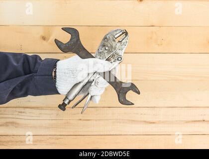 Working hand in glove holding a Spanner and Adjustable wrench with wall wood background Stock Photo