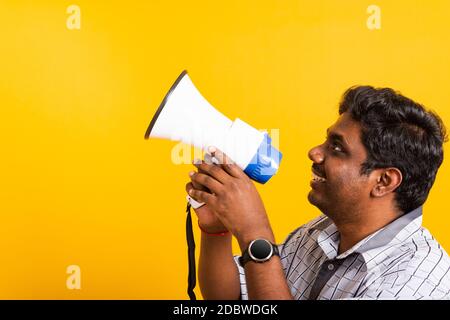 Asian happy portrait young black woman standing to make announcement message shouting screaming in megaphone, studio shot isolated on yellow backgroun Stock Photo