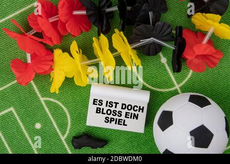 Soccer Ball with flower necklace in the colors of german flag and calendar. Es ist doch bloss ein Spiel in german language means Its only a game Stock Photo