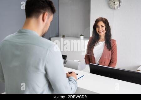 Client Signing Invoice At Hotel Reception Desk Stock Photo