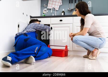 Plumber Cleaning Drain And Pipe In Kitchen Stock Photo