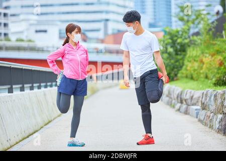 Young Man And Woman Stretching With A Face Mask Stock Photo