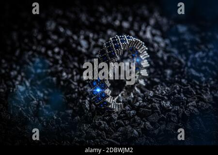 Silver ring with blue stones on black coal background Stock Photo