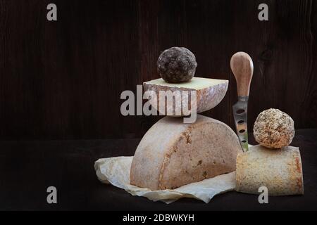 Heads of hard home-made cheese lie on a napkin. Photo on a dark background. Cheese knife. The concept of still life. Copy o space. Stock Photo