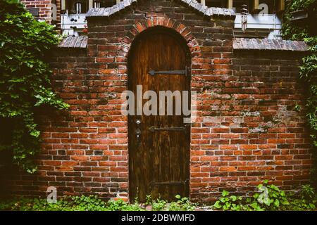 An Old Wooden Door in a Worn Brick Facade Stock Photo