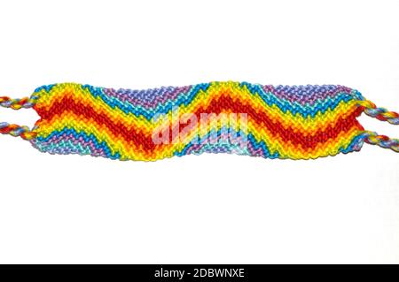 Woven DIY friendship bracelet handmade of embroidery bright thread with knots isolated on white background. Stock Photo