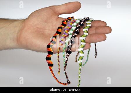 Woven friendship bracelets handmade of thread on males hand. Stock Photo