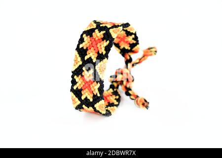 Selective focus of woven DIY friendship bracelet handmade of embroidery bright thread with knots isolated on white background. boho Stock Photo