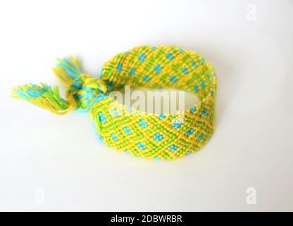 Selective focus of woven DIY friendship bracelet handmade of embroidery bright thread with knots isolated on white background. boho Stock Photo