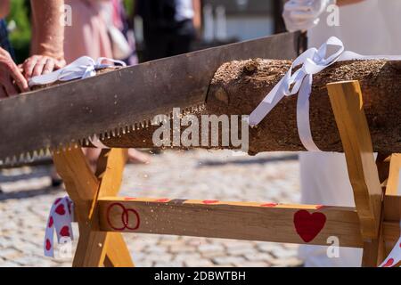Bride and groom cutting wood log on sawhorse with copy space at wedding day Stock Photo