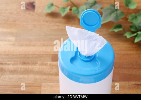 plastic tube shaped box of wet tissue paper on wooden table Stock Photo