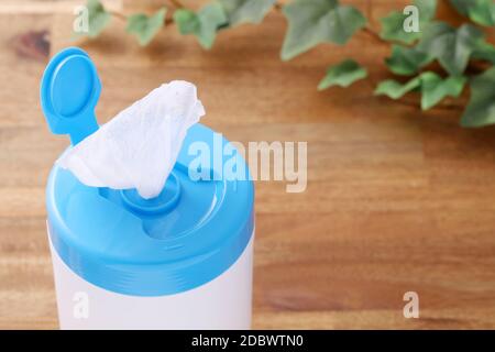 plastic tube shaped box of wet tissue paper on wooden table Stock Photo