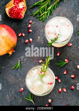 Autumn and winter cocktails idea - white sangria with rosemary, pomegrante and lemon juice and ingredients on black cement background. Copy space. Top Stock Photo