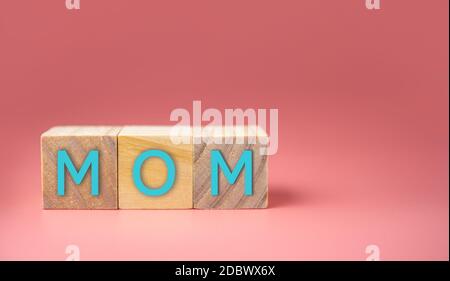 MOM Word Written In Wooden Cube on pink background. Mother's day concept. Stock Photo