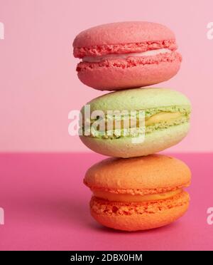 stack of baked macarons on pink background, delicious dessert made from almond flour, close up Stock Photo