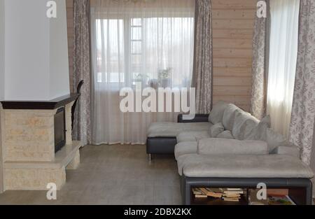 Light living room interior with fireplace, spacious windows, sofa and wooden trim Stock Photo