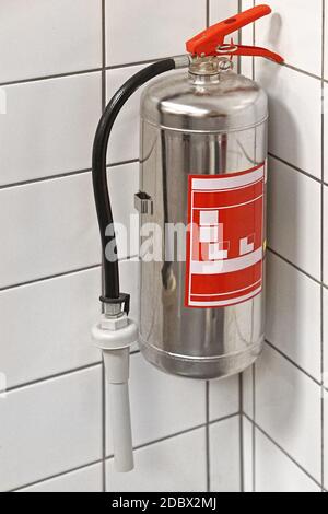 Silver fire extinguisher in building corner Stock Photo