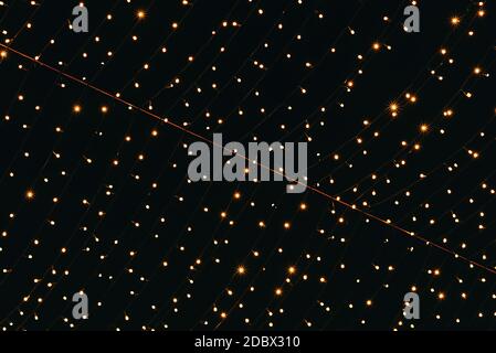 Many lightbulbs hanging on cable as garland decorative in festival isolated on dark night sky background, beautiful design of light string Stock Photo