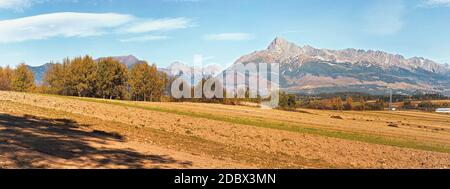 Mount Krivan peak Slovak symbol with blurred autumn coloured trees and dry field in foreground wide panorama, Typical autumnal scenery of Liptov regio Stock Photo