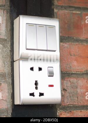 Three-key switch gray on the wall a plastic mechanical switch. The concept of energy savings. Closeup of Light Switch with copy space to the side. Stock Photo