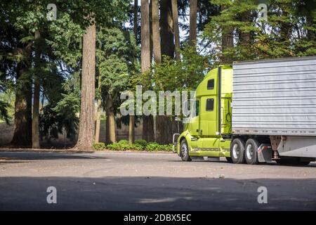 Bright green big rig industrial semi truck tractor with refrigerator semi trailer carry frozen food for delivery and running on the rest area parking Stock Photo