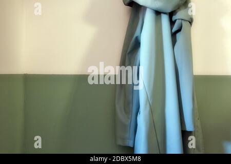 Green retro raincoat hanging on a half white half green wall in modern hallway of a house. modern style cozy Stock Photo
