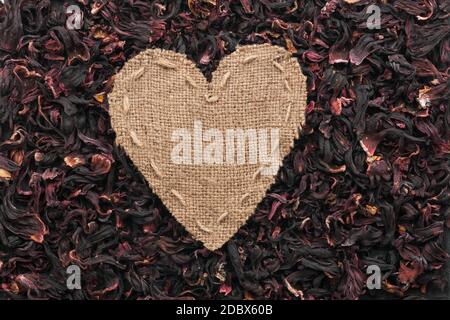 Frame in the shape of heart made of burlap with dried hibiscus, with space for your text Stock Photo