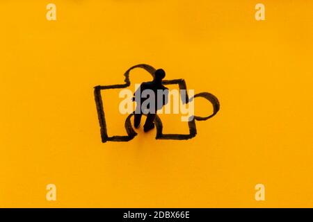 Miniature figurine posed as businessman in front of puzzle piece, solution concept image