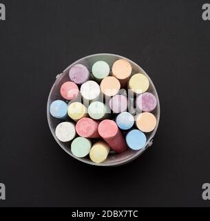 multicolored chalk in a plastic bucket on a black background, top view Stock Photo